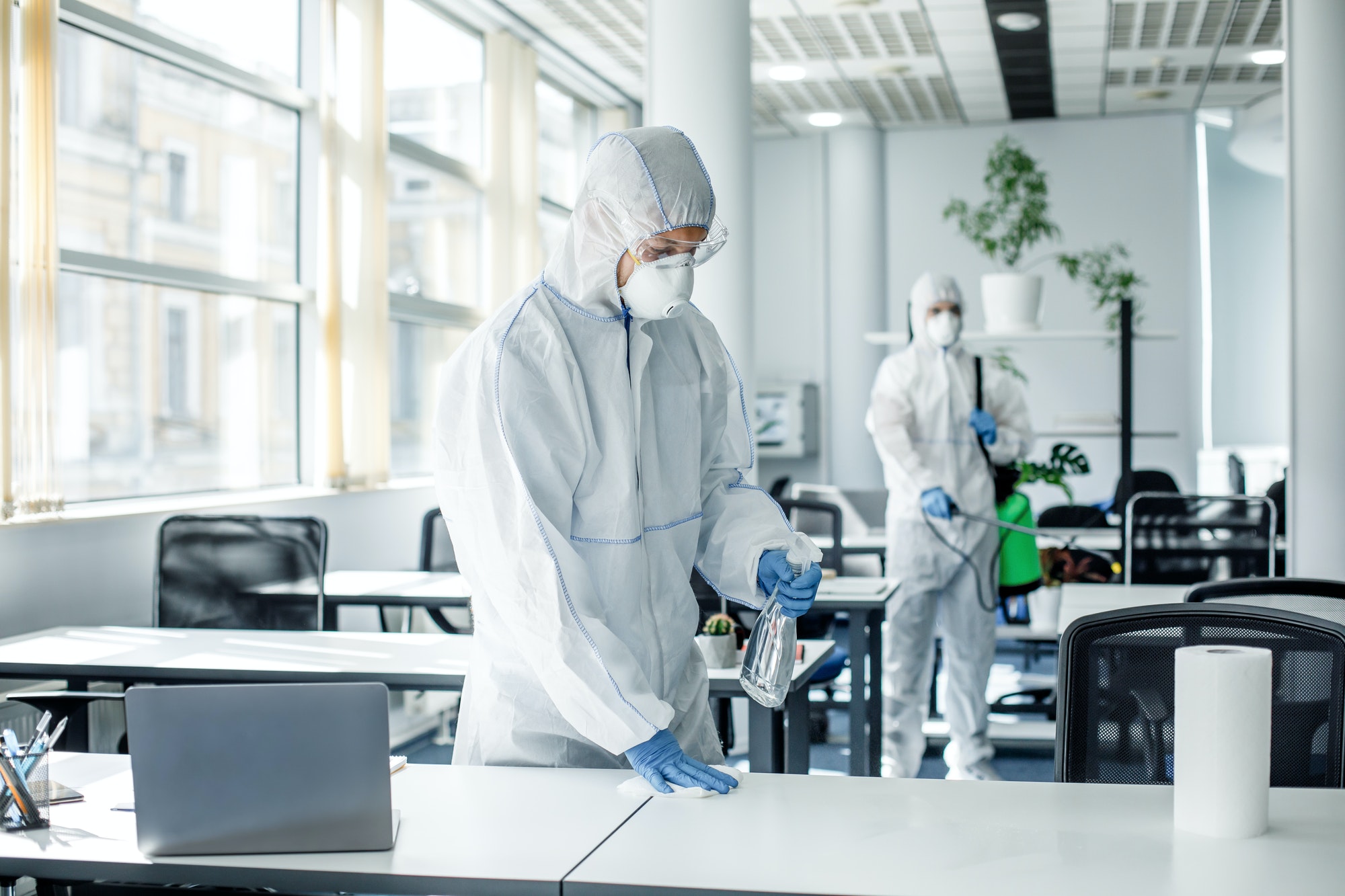 Disinfection of premises after work during covid-19 epidemic. People in hazmat suits, goggles and