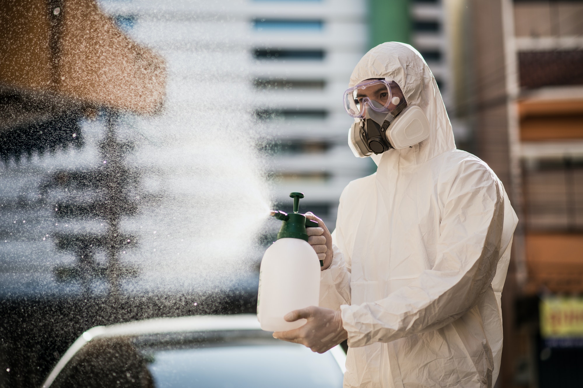 Disinfection specialist in PPE suit performing spray public decontamination